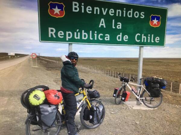 voyageur a velo devant panneau entree au chili